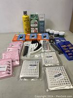 Image showing a yellow can of Got2b hair spray, pink packets of false eyelashes, nail rhinestone stickers, small cosmetic jars, and hair curling rods.