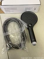 Photo showing the handheld shower head and 60 inch hose still in plastic packaging next to the product box.
