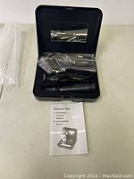 Open black carrying case showing the rechargeable shaver and attachments neatly placed inside along with the power cord and a user manual.