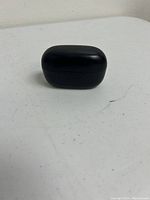 Closed black charging case placed on a white surface.