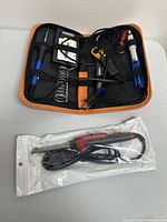 Soldering iron kit with case, soldering iron, stand and accessories and additional packaged soldering iron below it.