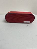 Photo of red Sony Bluetooth wireless speaker front and top_right sides visible, showing logo and buttons