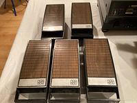 Five plastic 8-track tape storage cases with wood-grain lids and logos, arranged on a table.