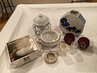 Assorted kitchen and decor items displayed including a chafing dish, ceramic bowl, boxed glassware, vase, candle holders, small cup, and ashtray.