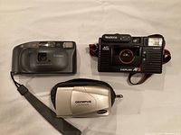 Top-down shot of three compact film cameras on white background
