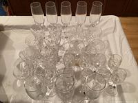 Top-down view of assorted crystal glasses showing variety of shapes and sizes on white cloth.