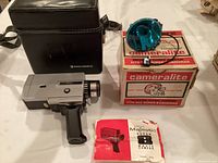 Photo showing the 8mm Eatons Majestic 25 TTL camera with pistol grip, black leather carrying case, printed user manual, and boxed Topmout Cameralite flash unit.