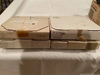 Four original boxes containing Edwin Knowles plates, each labeled with pattern name handwritten on the box sides.