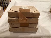 Four original boxed Edwin Knowles plates stacked on a table, boxes worn but marked with plate titles and dates from 1981.