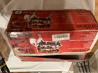 Photo showing sealed Grillmate portable gas BBQ in original packaging box with product image and specifications on the box.