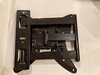 Black heavy duty metal TV wall mount bracket folded against a white surface.