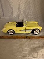 Side profile of the yellow 1957 Corvette diecast model showing length and detailing with a ruler for scale.