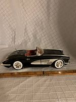 Side view of black diecast 1958 Corvette model car on measuring grid showing size.