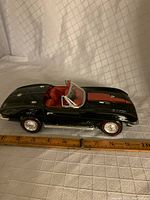 Side view of black 1967 Corvette model showing size against ruler, glossy paint, and red interior.