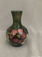 Front view showing green glazed squat vase with large pinkish-red anemone flower