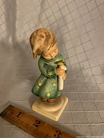 Front angle view of the angel figurine showing the candle and robe details, includes ruler for scale