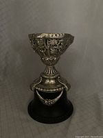 Full view of the silver trophy cup or urn on wood base, showing overall shape and design.
