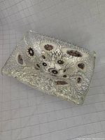 Top-angle view of rectangular Murano glass bowl showing silver flecks and embedded floral millefiori pattern.