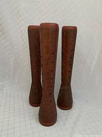 Front view of three vintage wooden spools standing upright, showing their shape, holes, and grooved bases.
