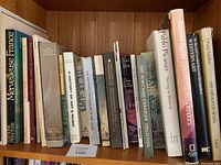 Books stacked on wooden bookshelf showing titles mostly about art, music, and culture such as Merveilleuse France, History of Art & Music, Picasso, Modigliani, and others.