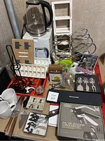 Overview photo of the kitchen and bar utensils including wine racks, kettle, ice trays, and serving utensils arranged on a table