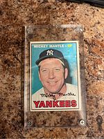 Front of 1967 Topps Mickey Mantle #150 card in acrylic case on countertop