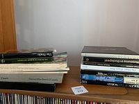 Two stacked piles of books on a wooden shelf showing many art and film related titles including multiple National Film Board of Canada publications.