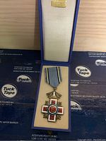 The medal in the presentation box, showing the medal and ribbon inside a blue box with cream interior.