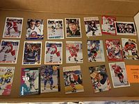 Photo of 20 assorted hockey cards arranged in a cardboard box, showing players from different teams and eras.