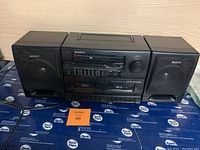 Front view of the Sony stereo cassette ghetto blaster with left and right speakers on either side, all in black plastic casing.