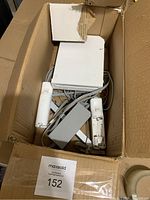 Top-down view showing white Nintendo Wii console, two Wii remotes with wrist straps, sensor bar, and power adapter in cardboard box.