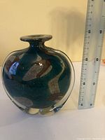 Side view of the vase showing its round shape, narrow neck, and flared rim next to a ruler for size reference