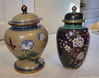 Front view of two imitation cloisonné jars with lids on, showing floral and bird designs with gold accents.