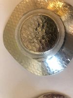 Bottom of pewter item showing hammered texture and stamped marks