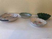Five ceramic bowls arranged in a single row showing different shapes, colors, and handles