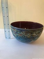 Side view of the blown glass bowl showing multicolored speckled pattern and glossy finish with a ruler for size reference.
