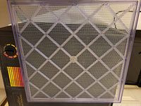Close-up front view of one of the removable mesh trays, showing purple plastic mesh and grid pattern for airflow.