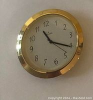 Close-up of round Bulova inset clock with gold-tone bezel and glass block