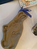 Photo of rabbit shaped cookie cutter with shovel on table, attached with blue ribbon.