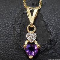 Close-up front view of the heart-shaped purple amethyst pendant with small white heart accent on gold chain.