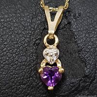 Front close-up photo of pendant showing heart-shaped amethyst and small heart accent with stones on 10K gold chain.