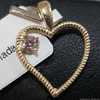 Front view of the 14K yellow gold heart pendant with pink diamond attached to a white tag.