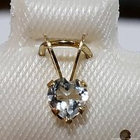 Close-up view of heart-shaped aquamarine gemstone pendant with yellow gold setting, showing the prongs and bail.