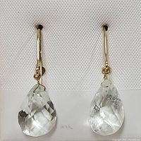 Front view of the pair of earrings showing the faceted pear-shaped green amethyst drops and yellow gold hooks.