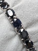 Row of oval blue sapphires set in sterling silver prong settings