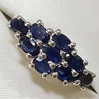 Close-up of the ring top showing nine oval blue sapphires in a prong setting on a sterling silver band.