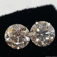Close up of two round cut moissanite stones showing faceting and brilliance.