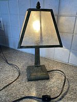 Small accent lamp turned on, showing the semi-transparent shade and metal base on a tiled countertop.
