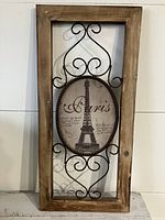 Full view of rectangular wooden frame with black metal scrollwork and oval Eiffel Tower image print