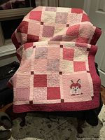 Full view of the pink and plum patchwork quilt with dog appliqué on front.